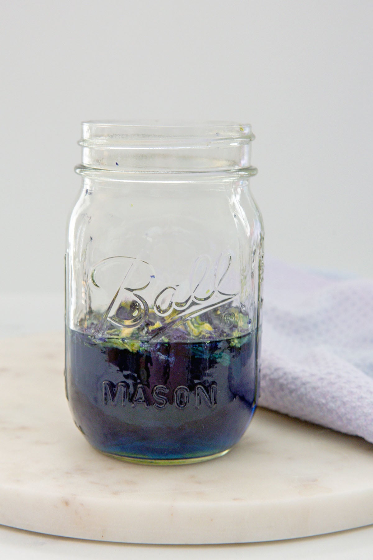 Butterfly pea flowers infusing into water in mason jar.