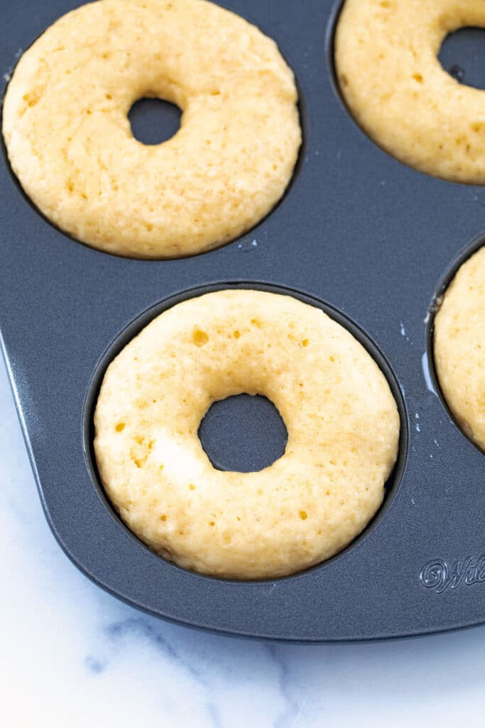 Closeup view of donuts just baked in pan.