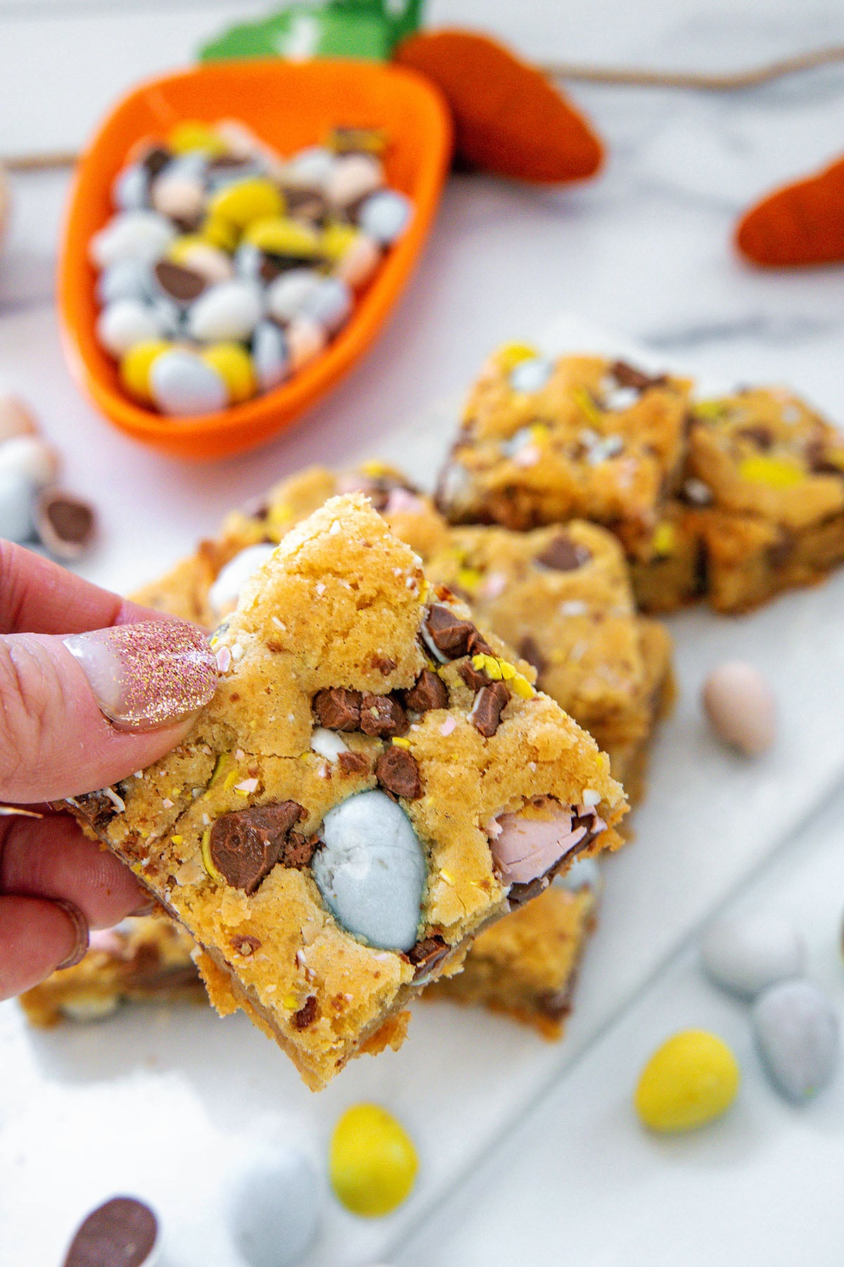 Cadbury Mini Egg blondie being held up with more in background.