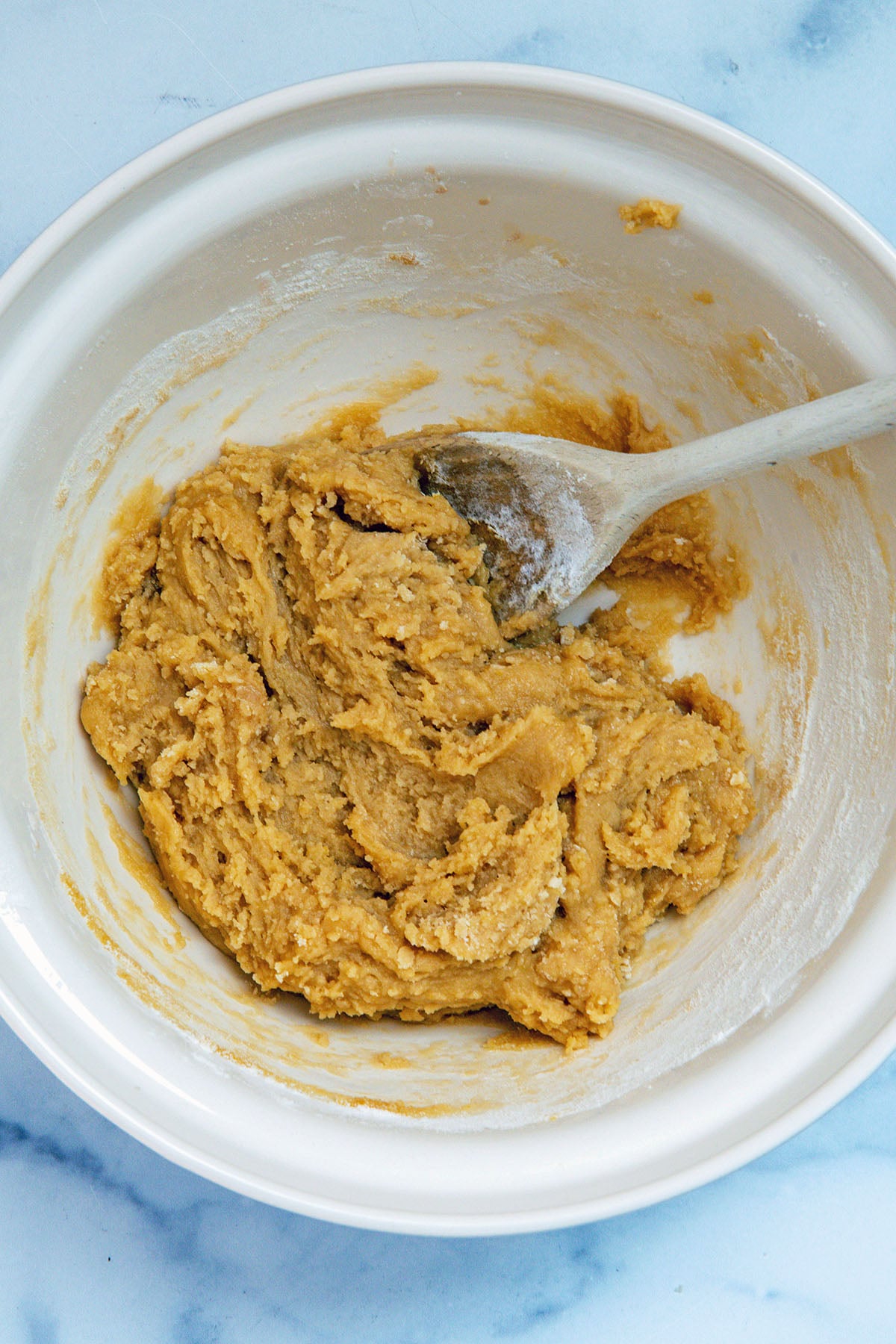 Blondie batter in mixing bowl with wooden spoon.