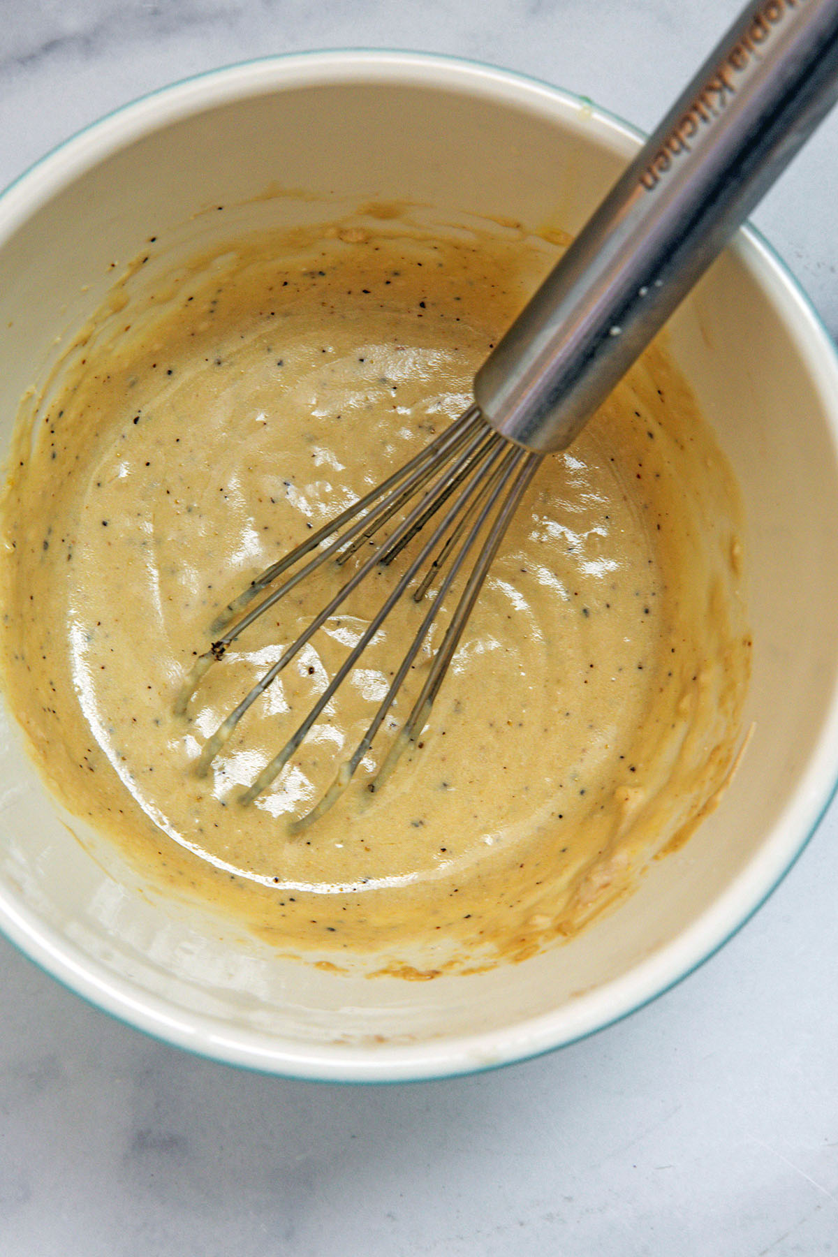 Caesar dressing in bowl with whisk.