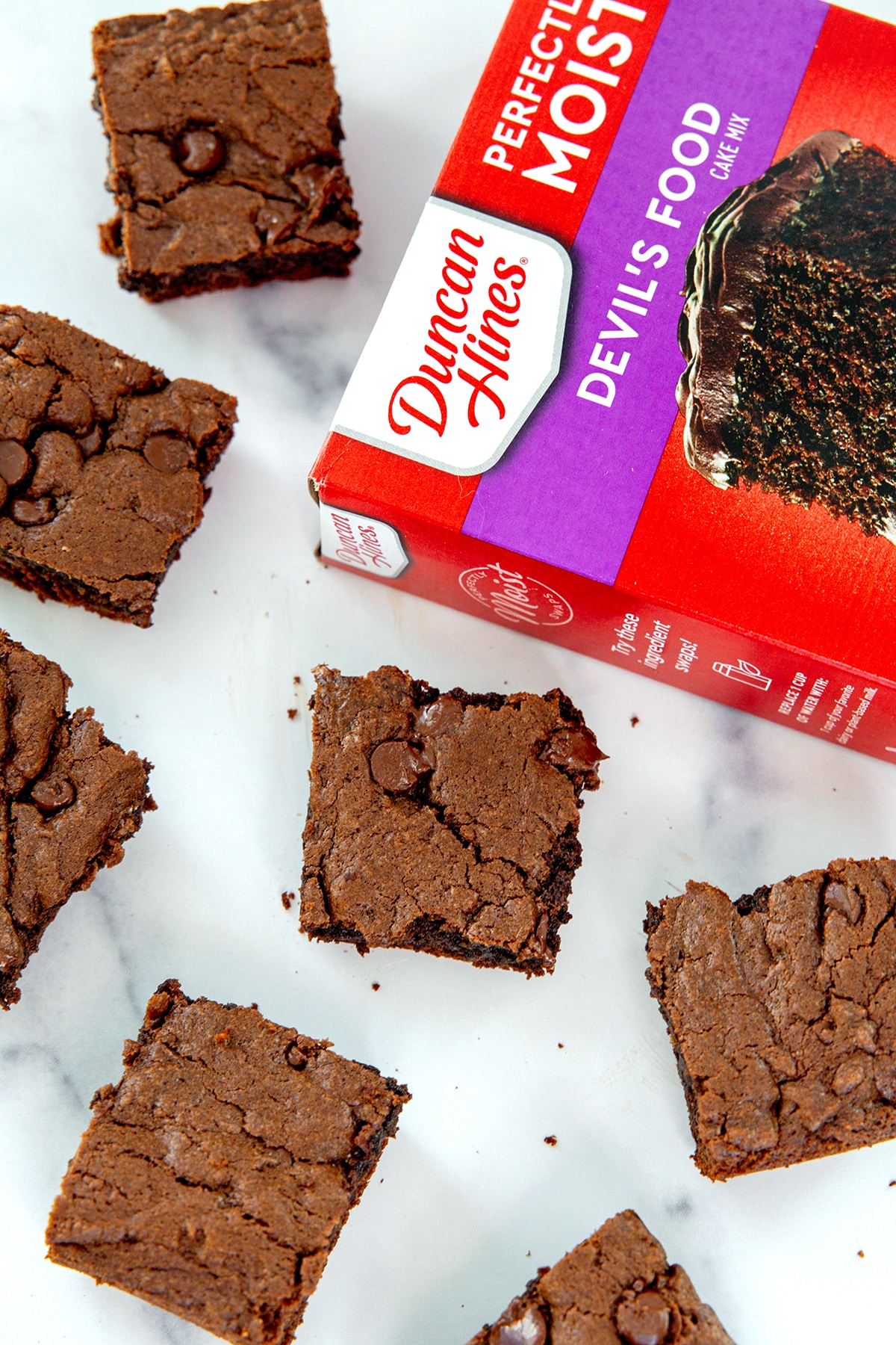 Brownie squares on a marble surface with box of cake mix.