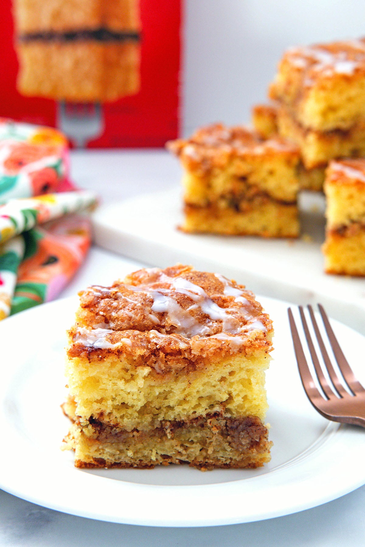Piece of cake mix coffee cake on a white plate with more slices and box of cake mix in background.