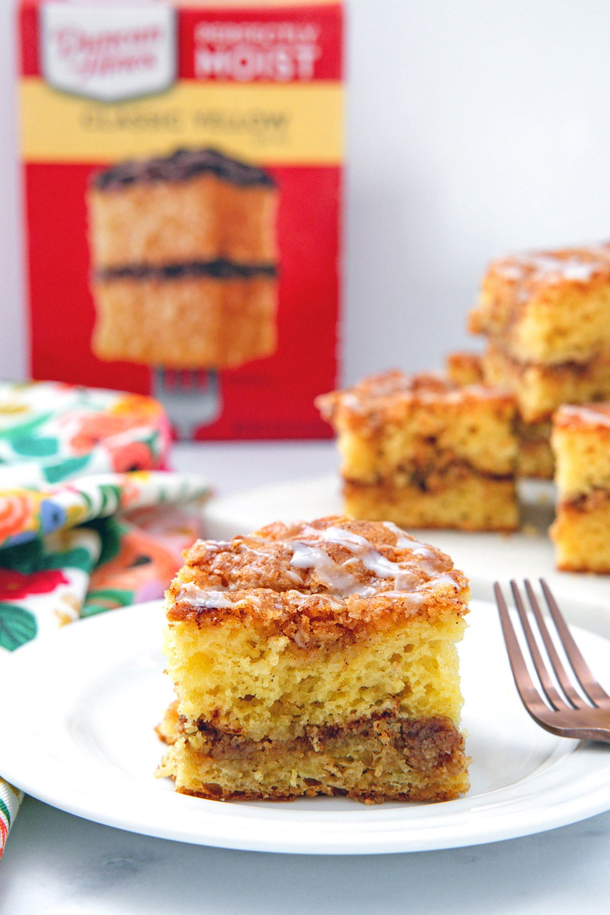 Head-on view of a slice of cake mix coffee cake with box of cake mix in background.