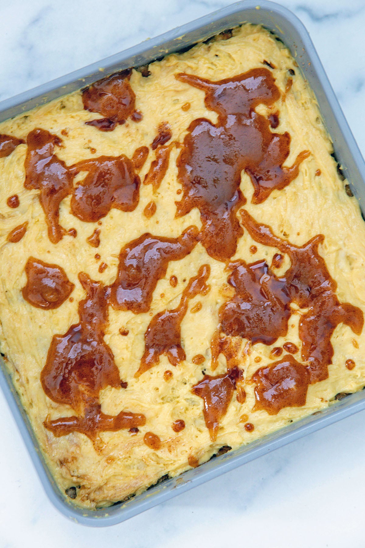 Coffee cake batter in square pan with brown sugar butter drizzle.