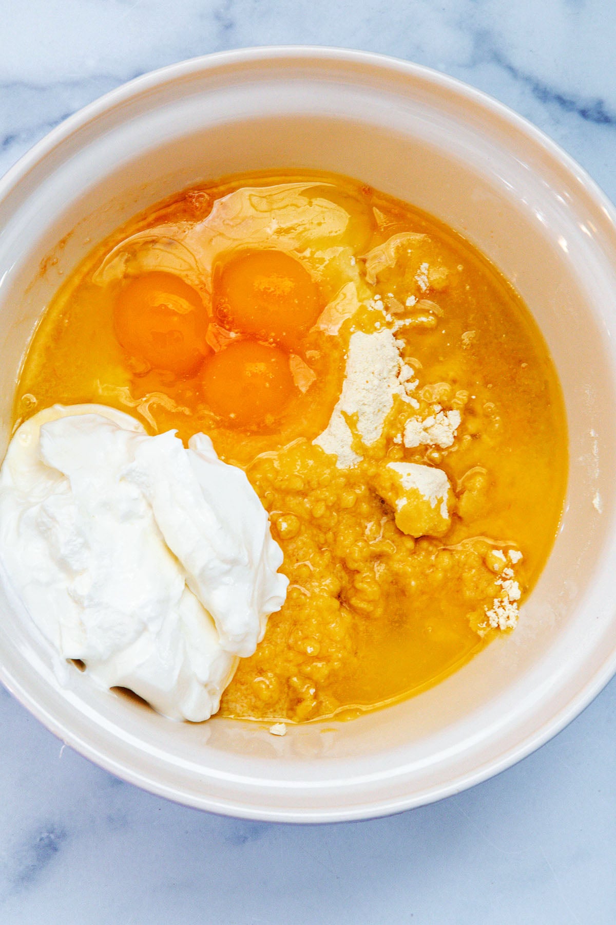 Cake mix, eggs, sour cream, butter, and oil in a mixing bowl.