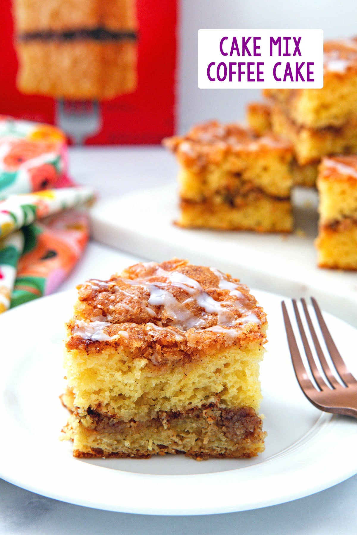 Piece of cake mix coffee cake on a white plate with more slices and box of cake mix in background and recipe title at top.