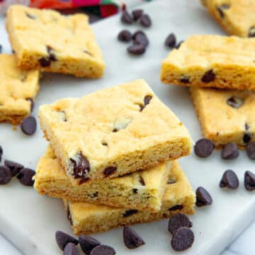 Closeup view of a stack of chocolate chip cake mix cookie bars with chocolate chips all around.