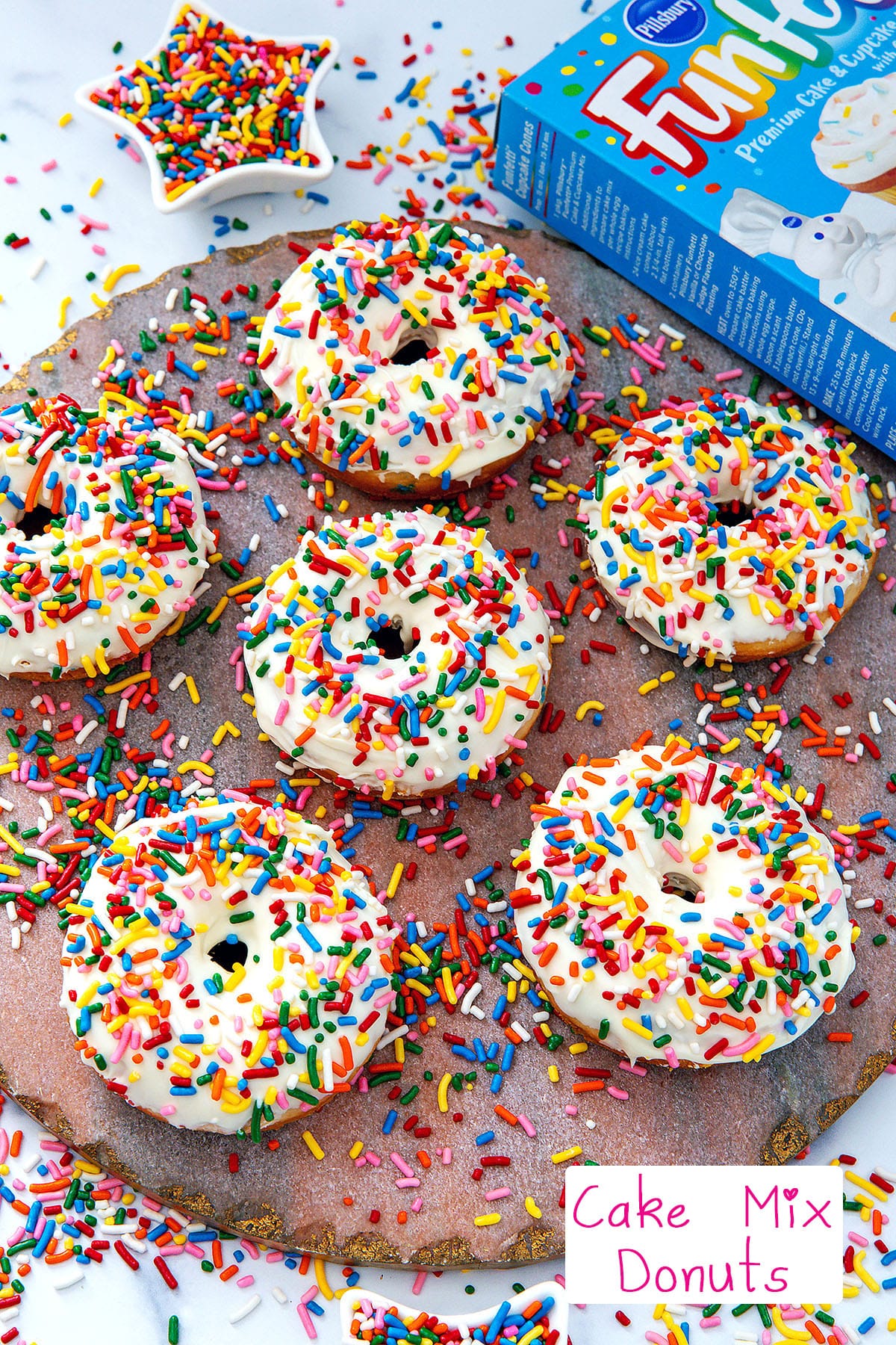 Overhead view of vanilla frosted cake mix donuts with rainbow sprinkles with box of Funfetti cake mix in background with recipe title at bottom.