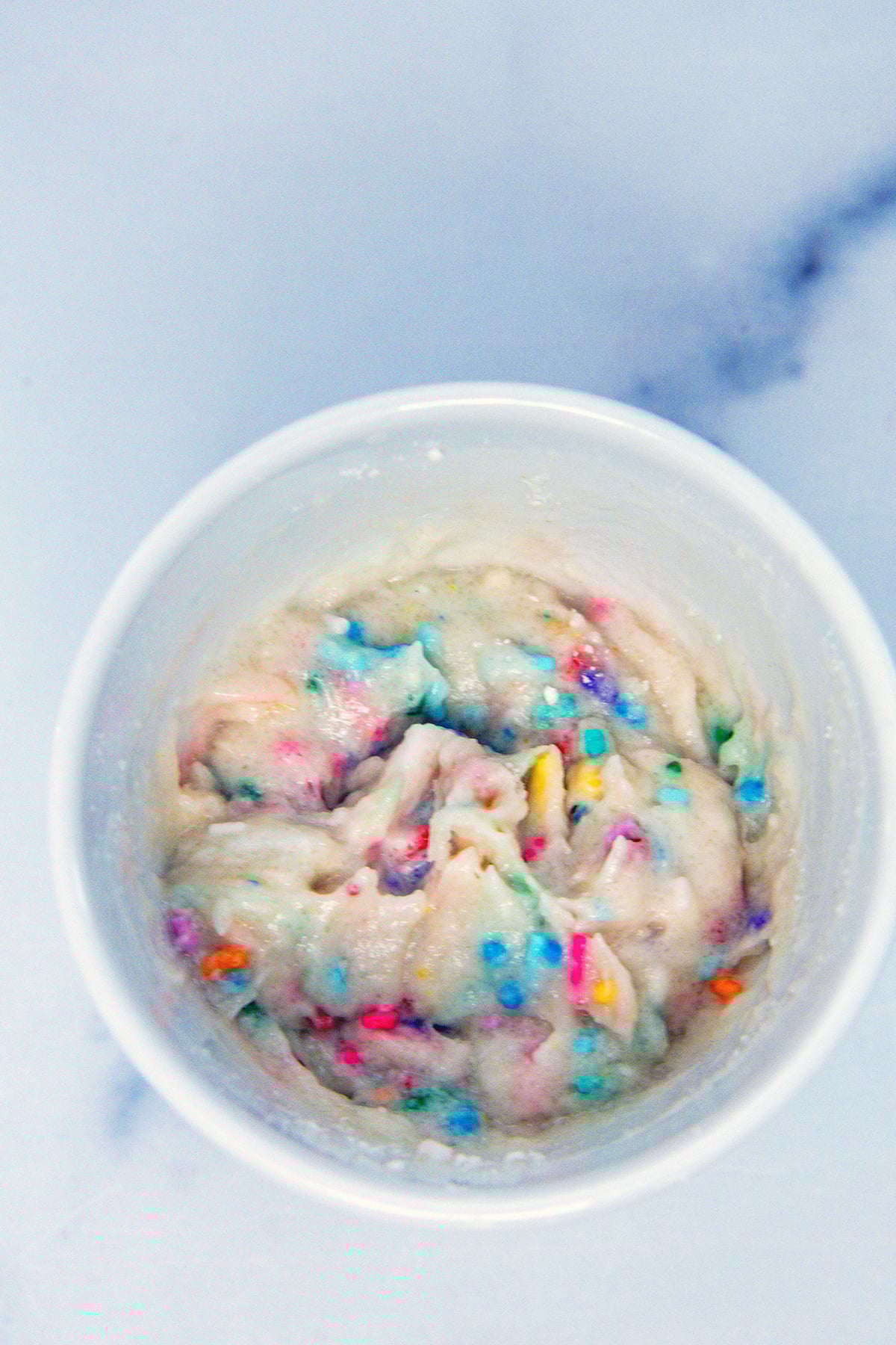 Overhead view of ingredients for cake mix mug cake in a white mug.