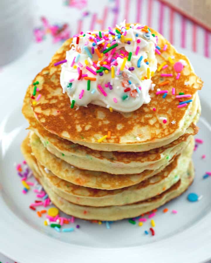 Stack of cake mix pancakes topped with frosting and sprinkles.