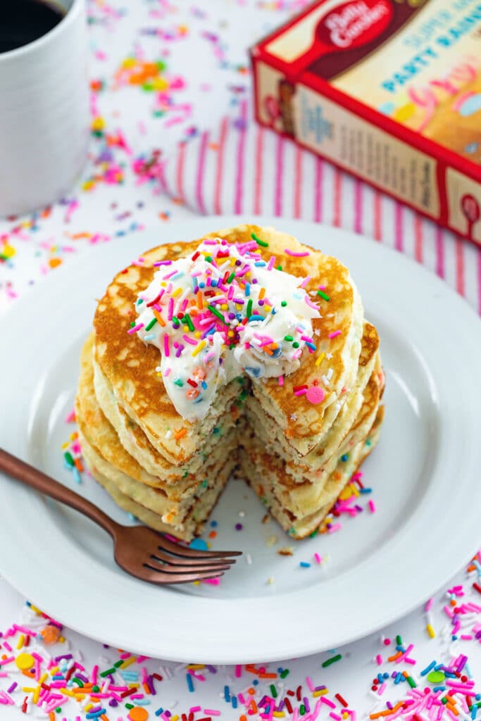 Cake mix pancakes with a portion cut out and a fork on the side with sprinkles all around.