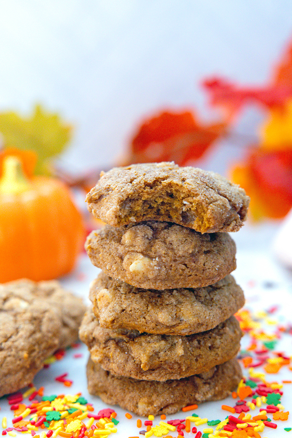 Head-on view of a stack of cake mix pumpkin cookies with sprinkles all around.