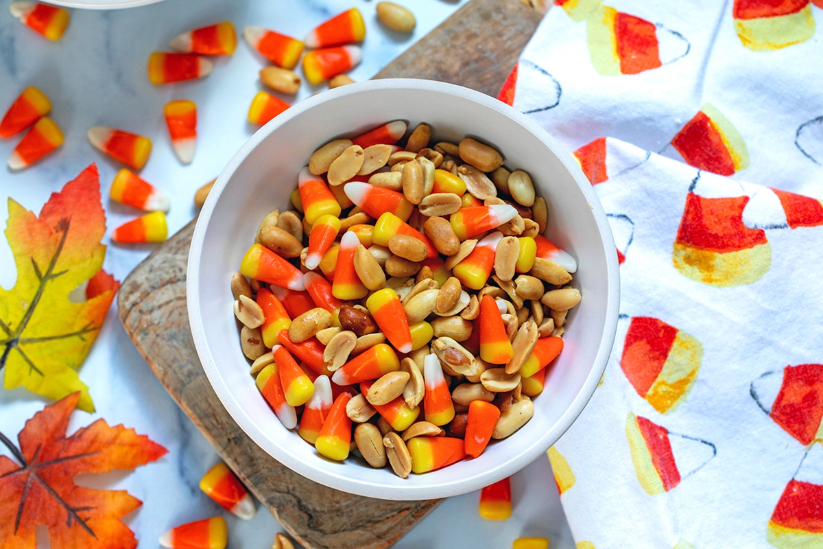 Overhead landscape photo of candy corn and peanuts in bowl.