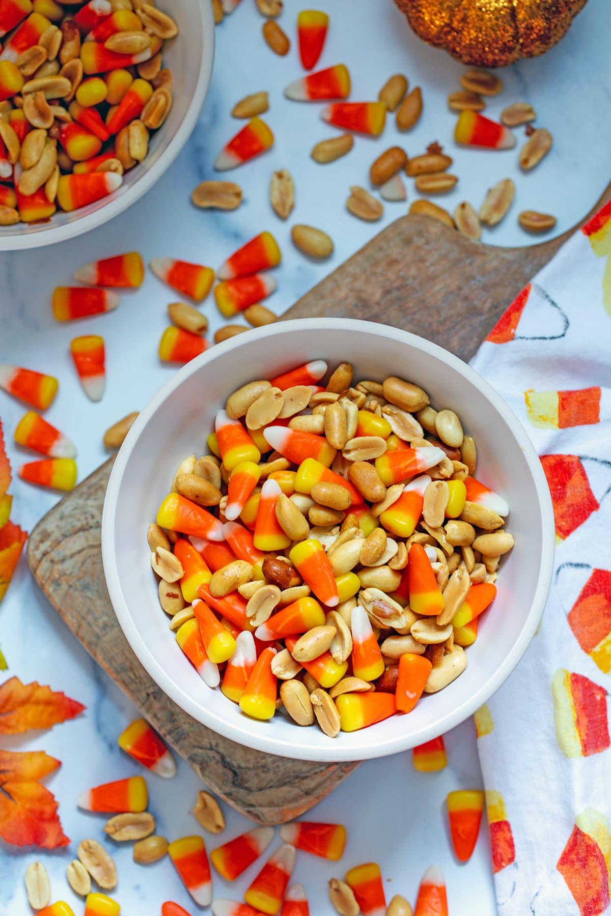 Candy Corn and peanuts mixed together in a bowl with more candies all around.