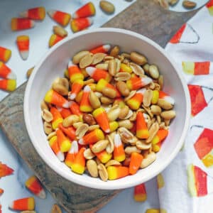 Overhead closeup view of a bowl of candy corn and peanuts.