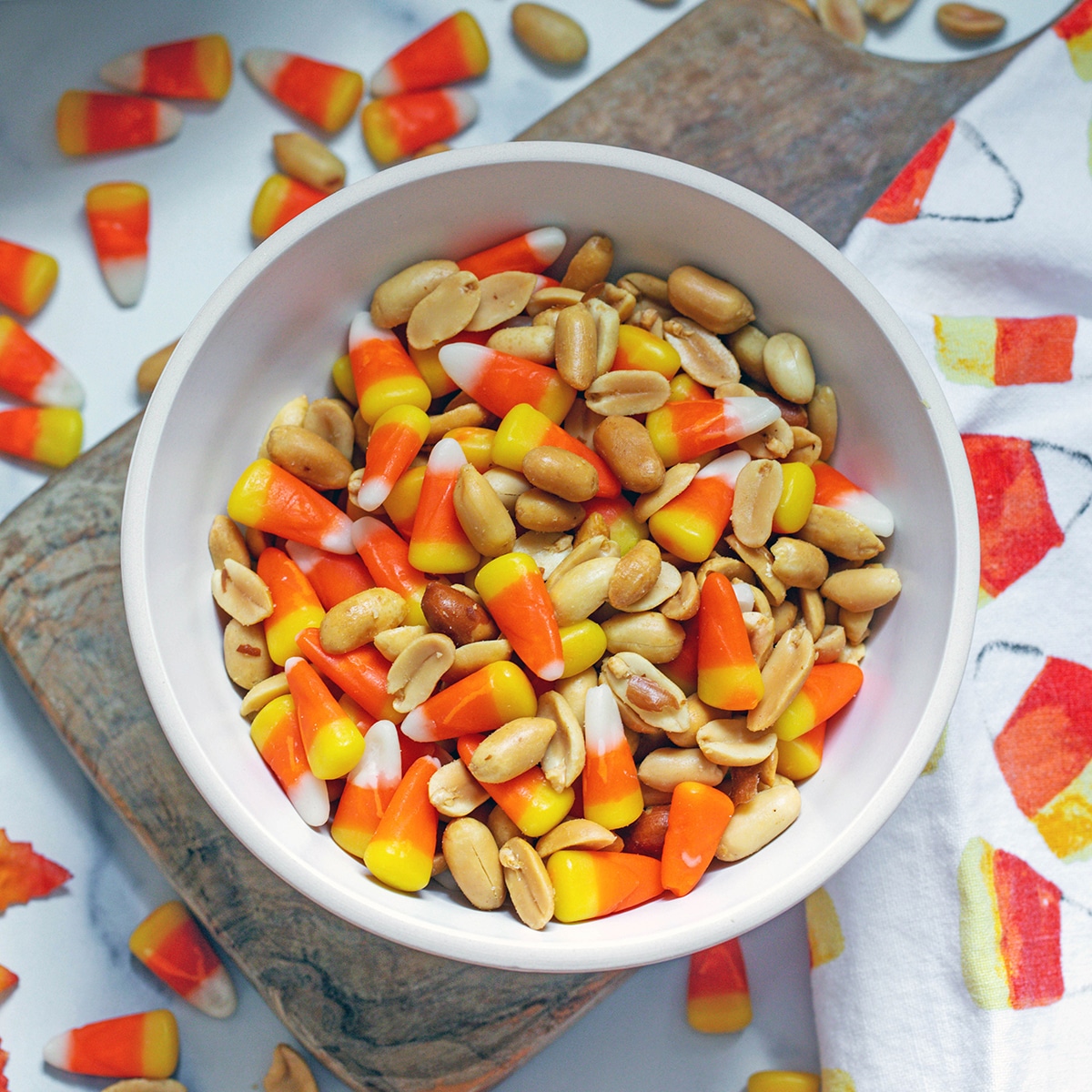 Overhead closeup view of a bowl of candy corn and peanuts.