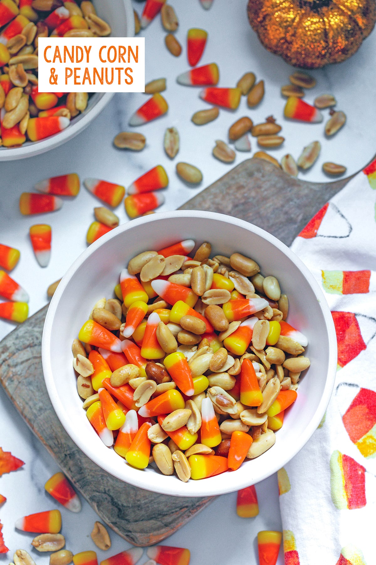 Overhead bowl of candy corn and peanuts with both ingredients spread all around in background, along with glitter pumpkin and recipe title at top.