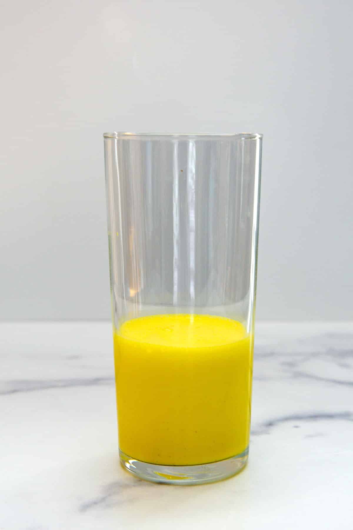 Glass filled ⅓ of the way with yellow milkshake.