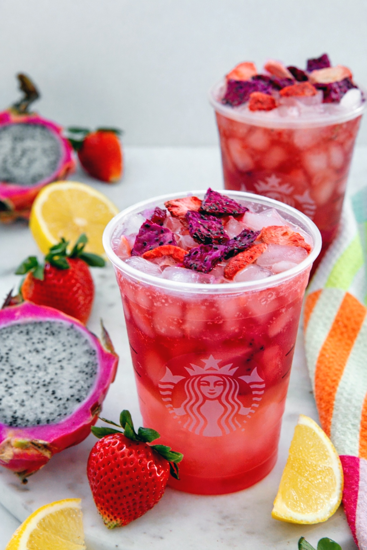 Overhead view of a Cannon Ball Drink in a Starbucks cup with strawberries, lemons, and dragon fruit all around.