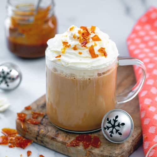 Closeup view of a caramel brulée latte with whipped ceram and caramel bit topping.