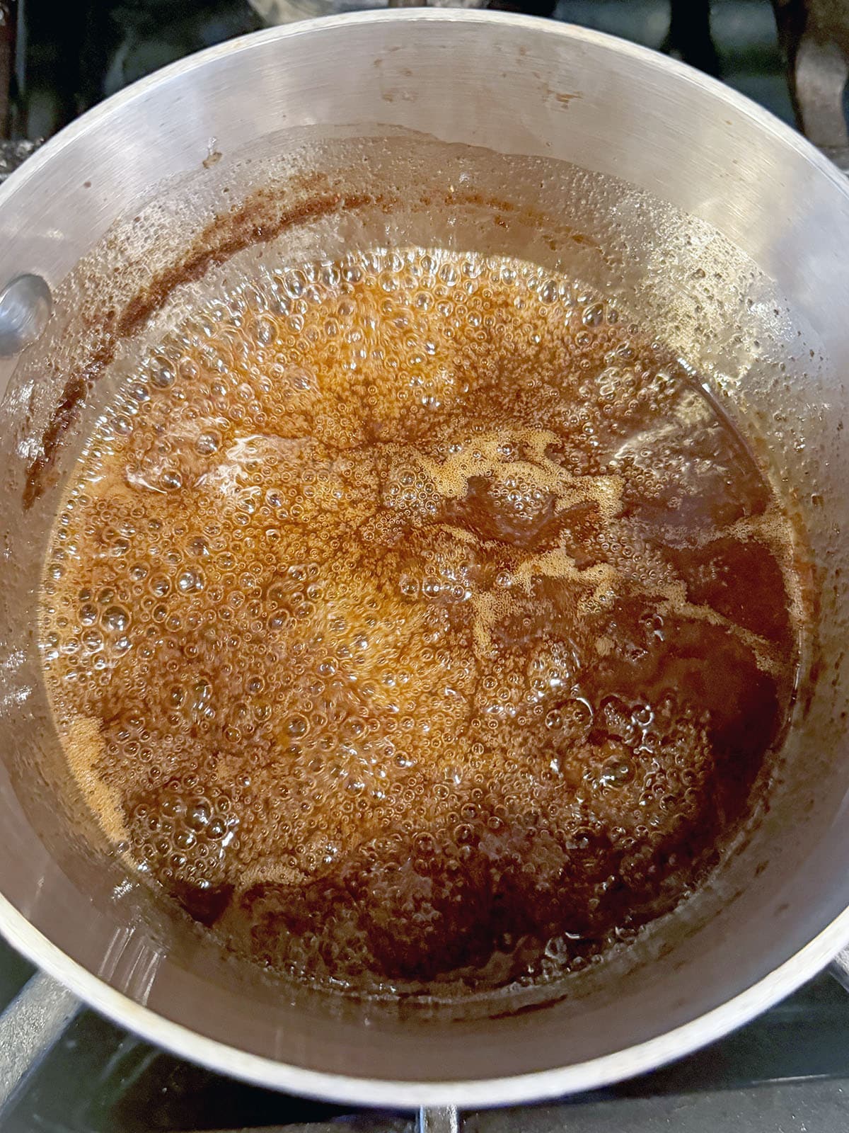 Caramel brulée sauce simmering in saucepan.