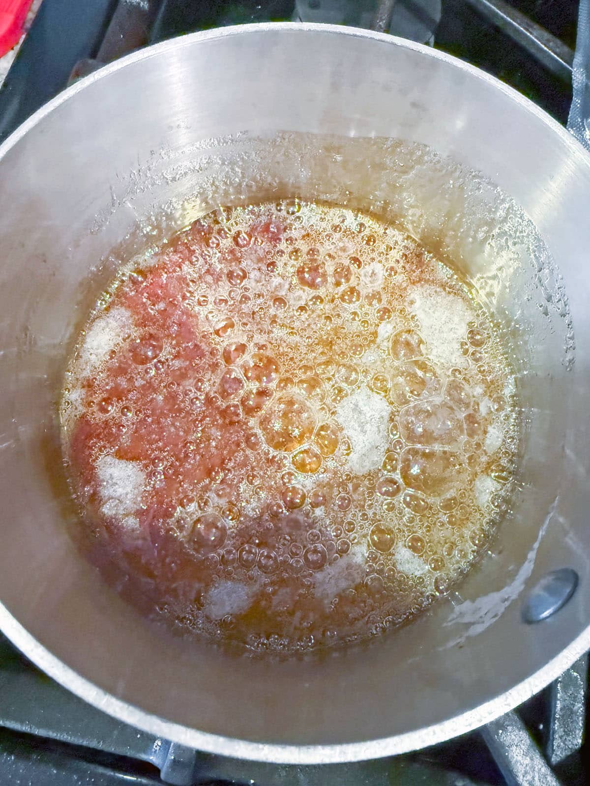 Sugar solution turning into caramel in saucepan.