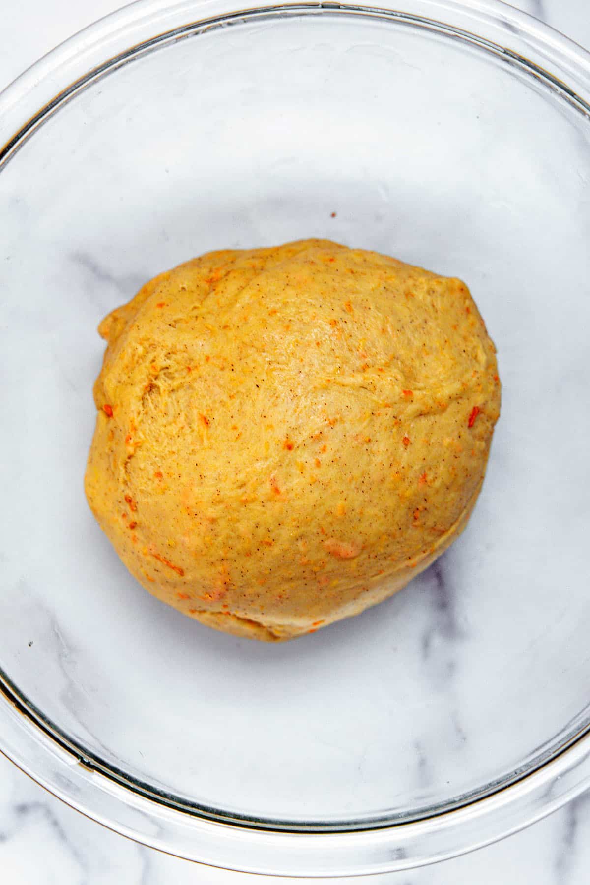 Carrot cake cinnamon roll dough ball in mixing bowl.