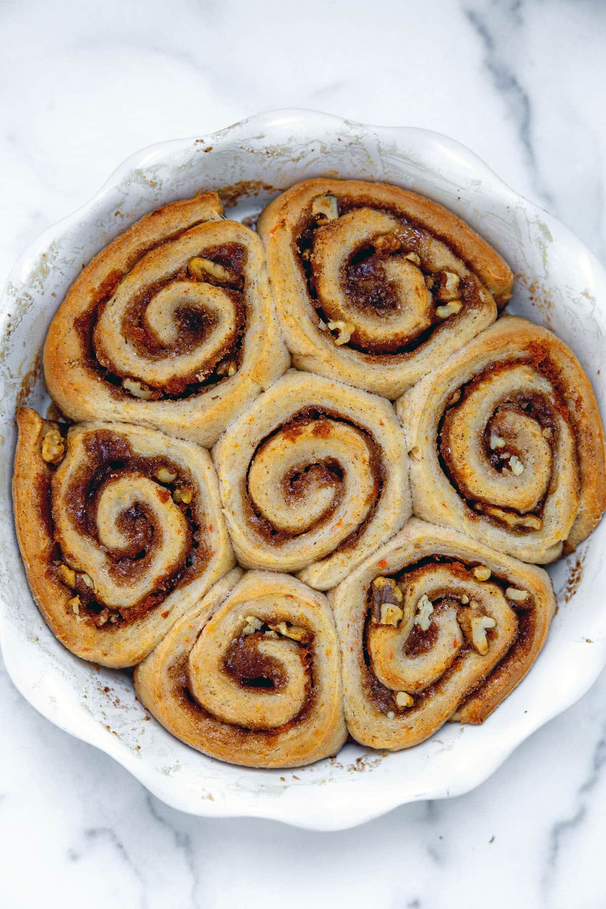 Baked carrot cake cinnamon rolls in pie dish.