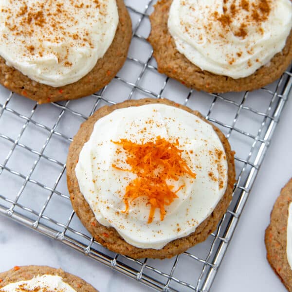 Closeup view of a carrot cake mix cookie with cream cheese frosting and shredded carrots on top.
