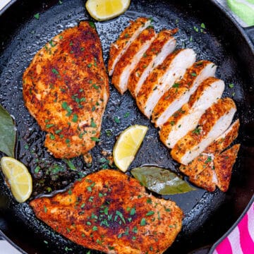 Closeup view of cast iron chicken breast, 2 whole breasts and 1 sliced.