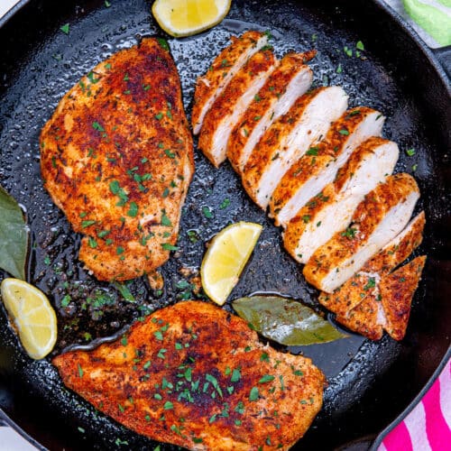 Closeup view of cast iron chicken breast, 2 whole breasts and 1 sliced.