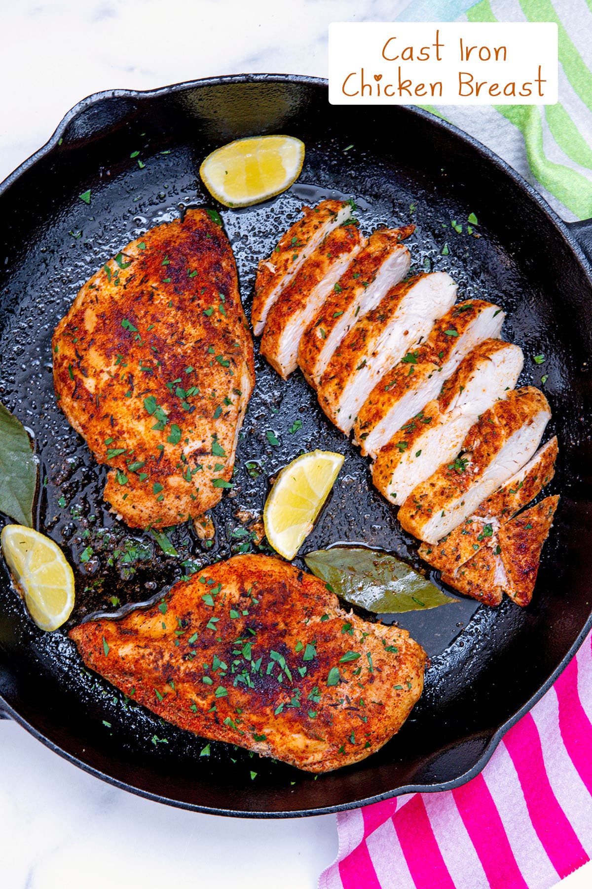 Overhead view of three chicken breasts in cast iron skillet, one sliced, with recipe title at top.