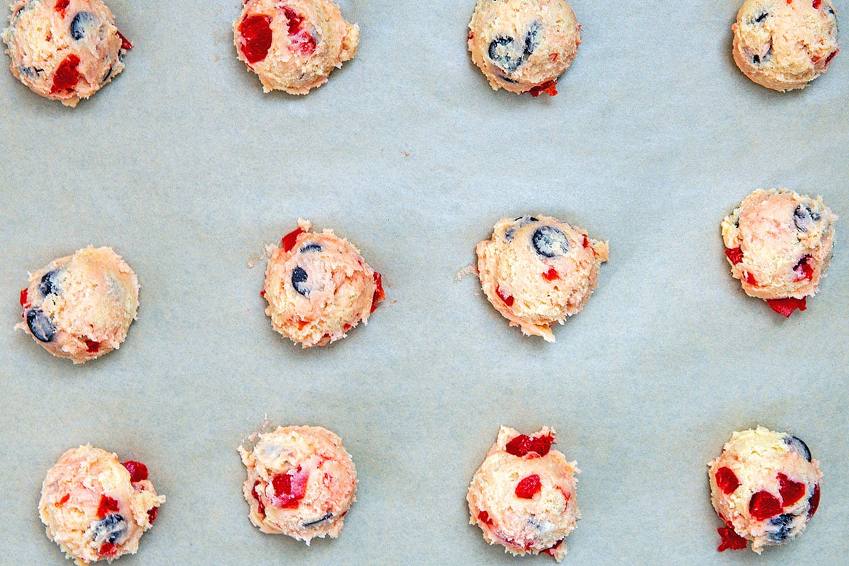 Cherry chocolate chip cookie dough scooped on cookie sheet.