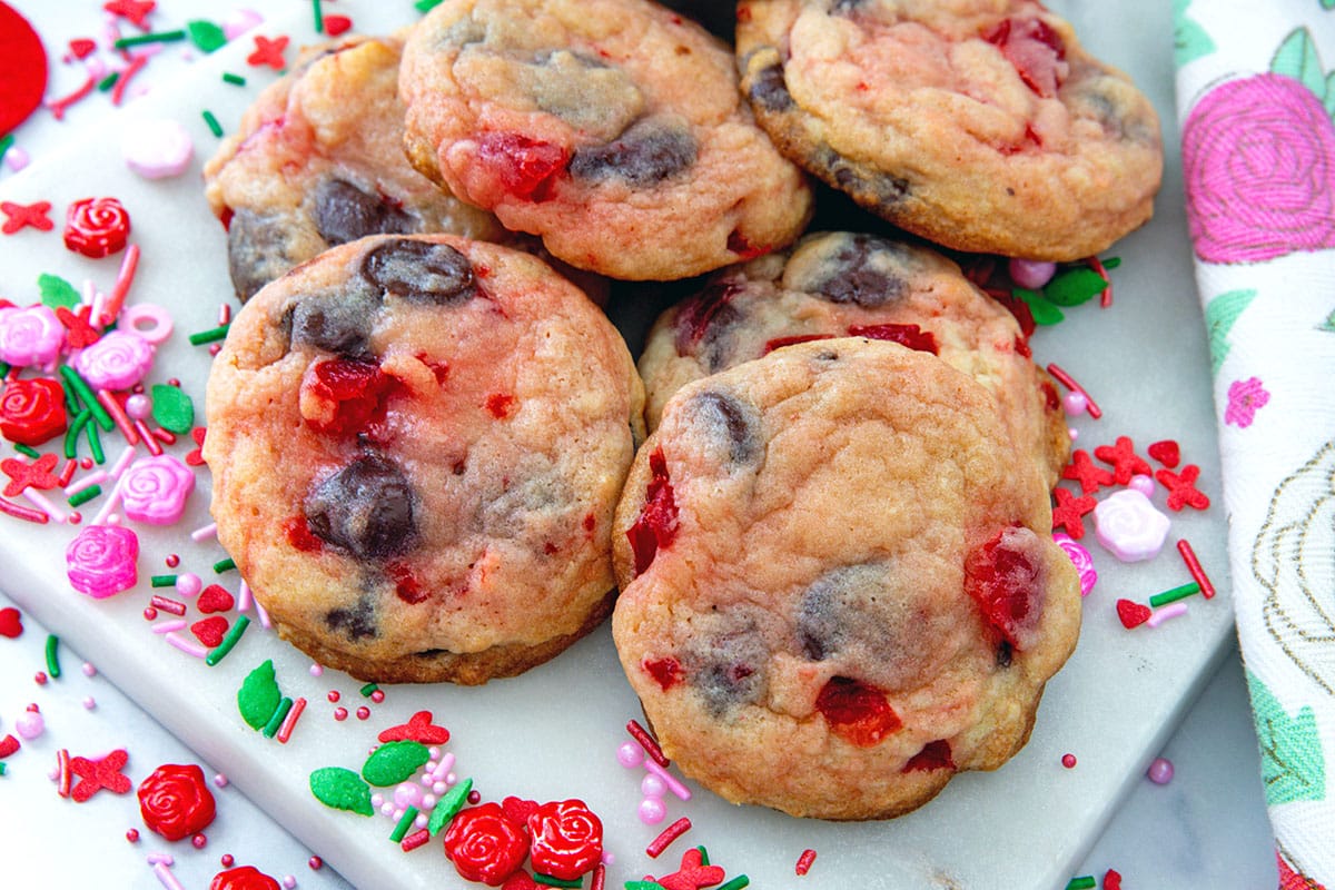 Landscape overhead view of cherry chocolate chip cookies with sprinkles all around.