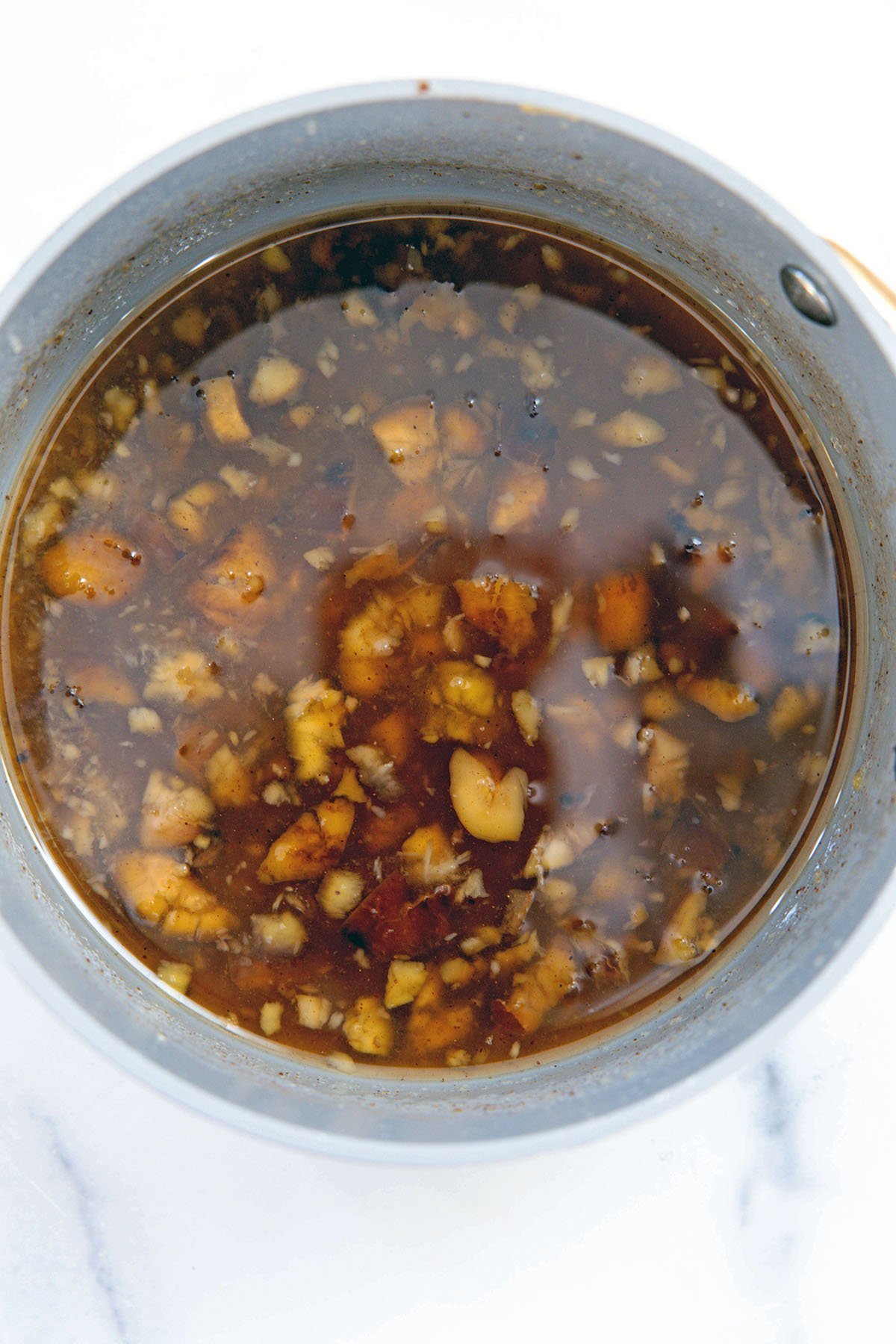 Overhead view of chopped chestnuts in saucepan with water and sugar.