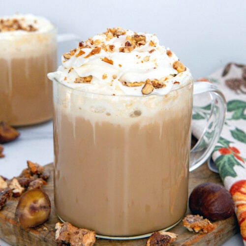 Closeup view of a Chestnut Praline Latte with whipped cream and praline crumble.