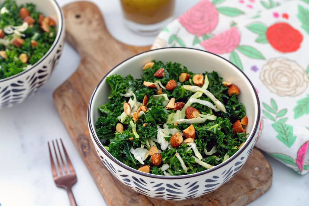 Head-on view of Chick-Fil-A kale salad on a wooden board with fork next to it.