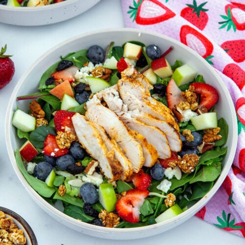 Closeup view of a Chick-Fil-A Market Salad made at home with grilled chicken, lettuce, blueberries, apples, strawberries, granola, and more.