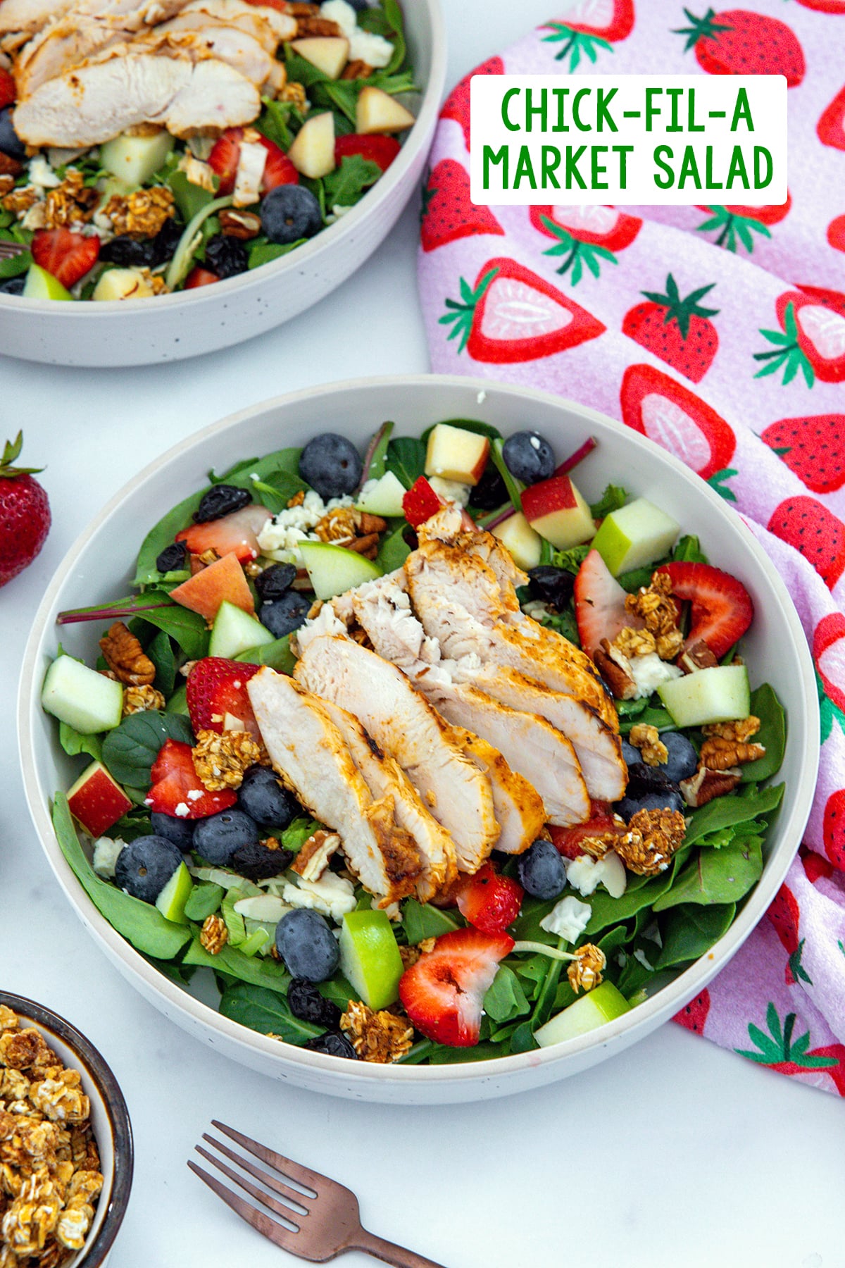 Overhead view of Chick-Fil-A Market Salad with grilled chicken, lettuce, apples, blueberries, strawberries, granola, and more with recipe title at top of photo.