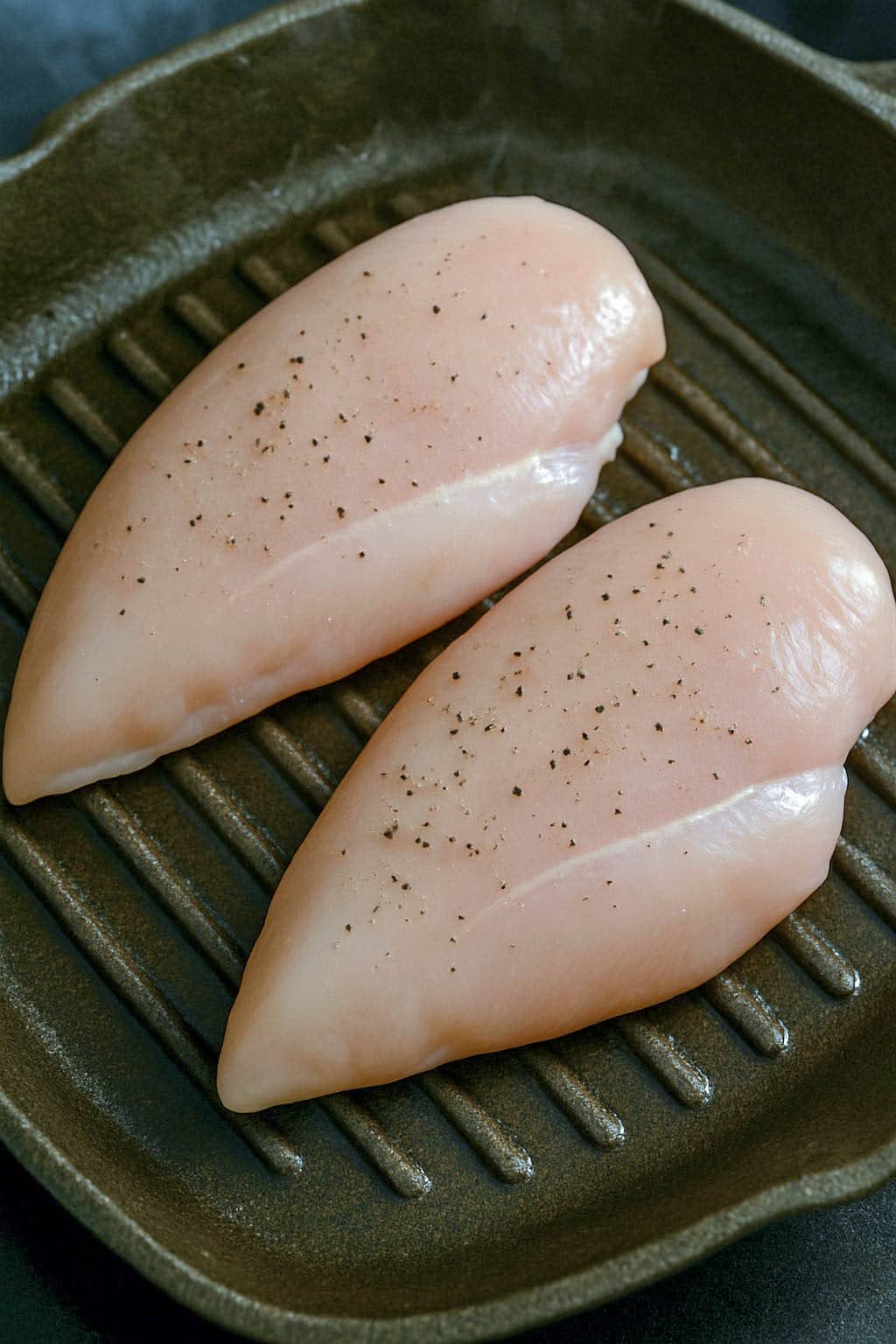 Raw chicken breast on grill pan.