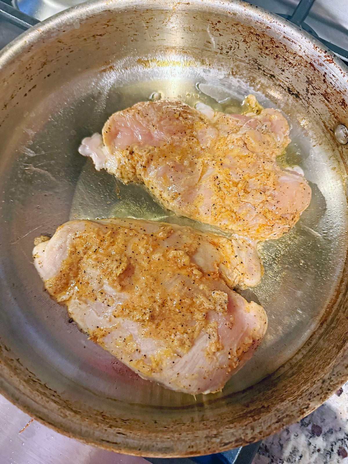 Chicken breasts with marinade in skillet.