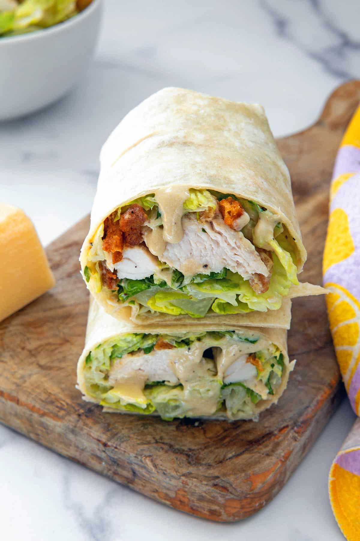 Closeup view of a chicken caesar wrap on a wooden board.