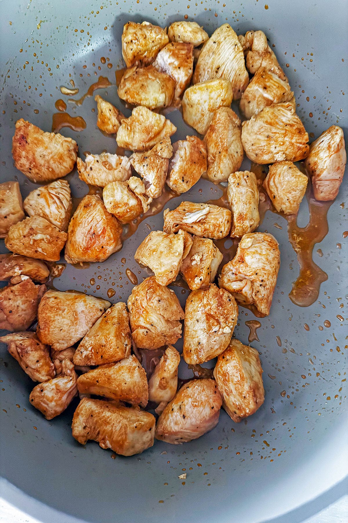 Chicken chunks cooking in skillet.