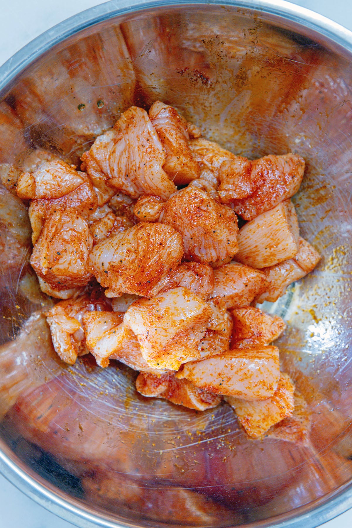 Chicken in bowl with spices.