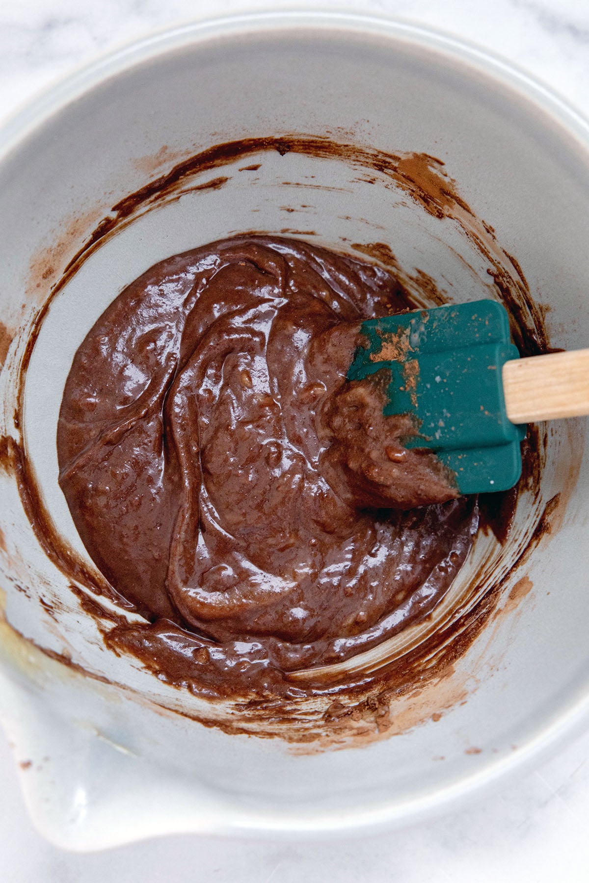 Chocolate batter in mixing bowl with rubber spatula.