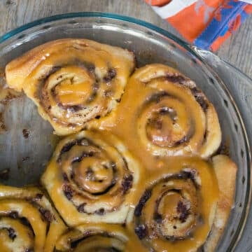 Closeup view of a plate full of chocolate chip cinnamon rolls with butterscotch icing.