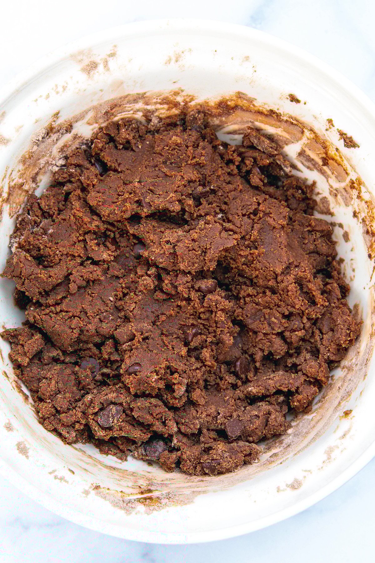 Overhead view of chocolate cookie dough in a mixing bowl.