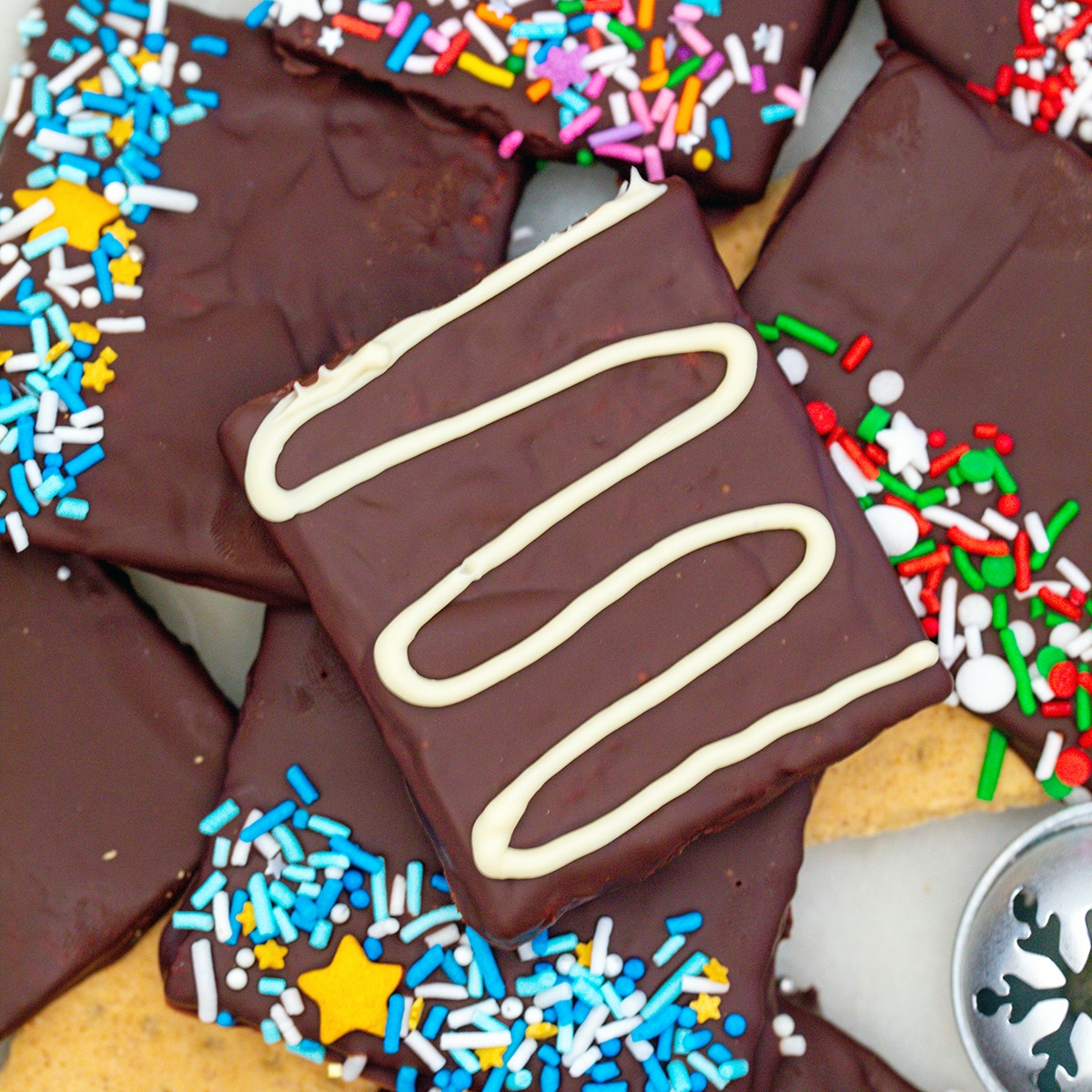 Closeup view of chocolate covered graham crackers with sprinkles and white chocolate.