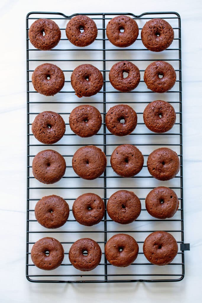 Mini chocolate donuts on cooling rack.